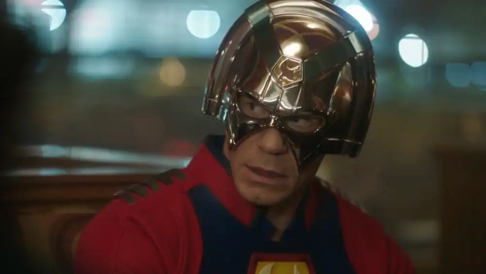 A metallic helmet worn by a character with a serious expression, in a scene from a superhero movie, emphasizing high-tech costume and cinematic design.