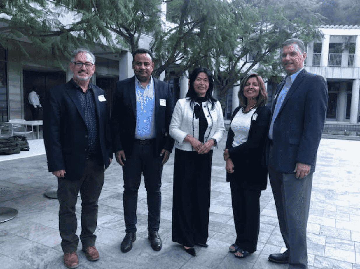 Group of diverse professionals at an outdoor corporate event, dressed in business attire, engaged in networking and socializing.