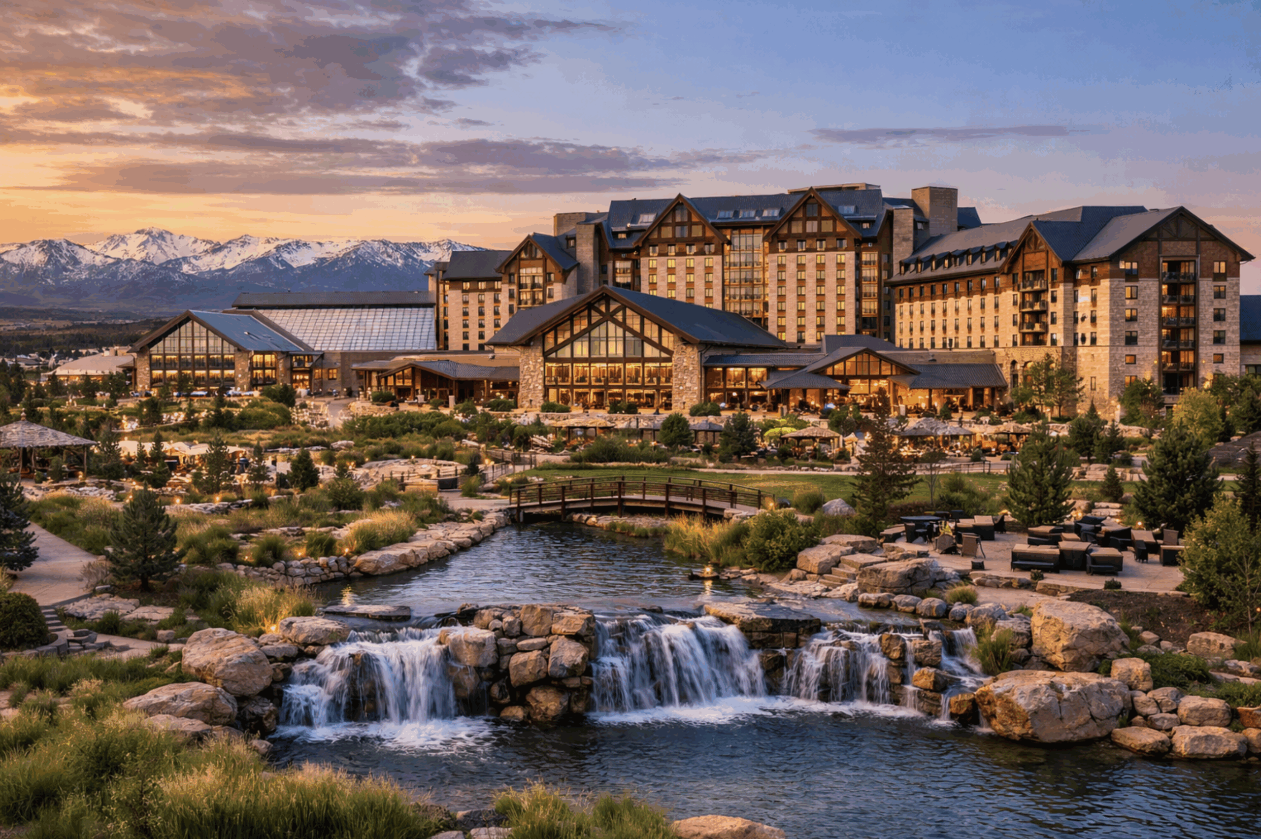 Luxurious mountain resort with modern architecture, scenic waterfalls, and stunning views of snow-capped peaks at sunset. Perfect destination for relaxation and outdoor adventures in a picturesque set.